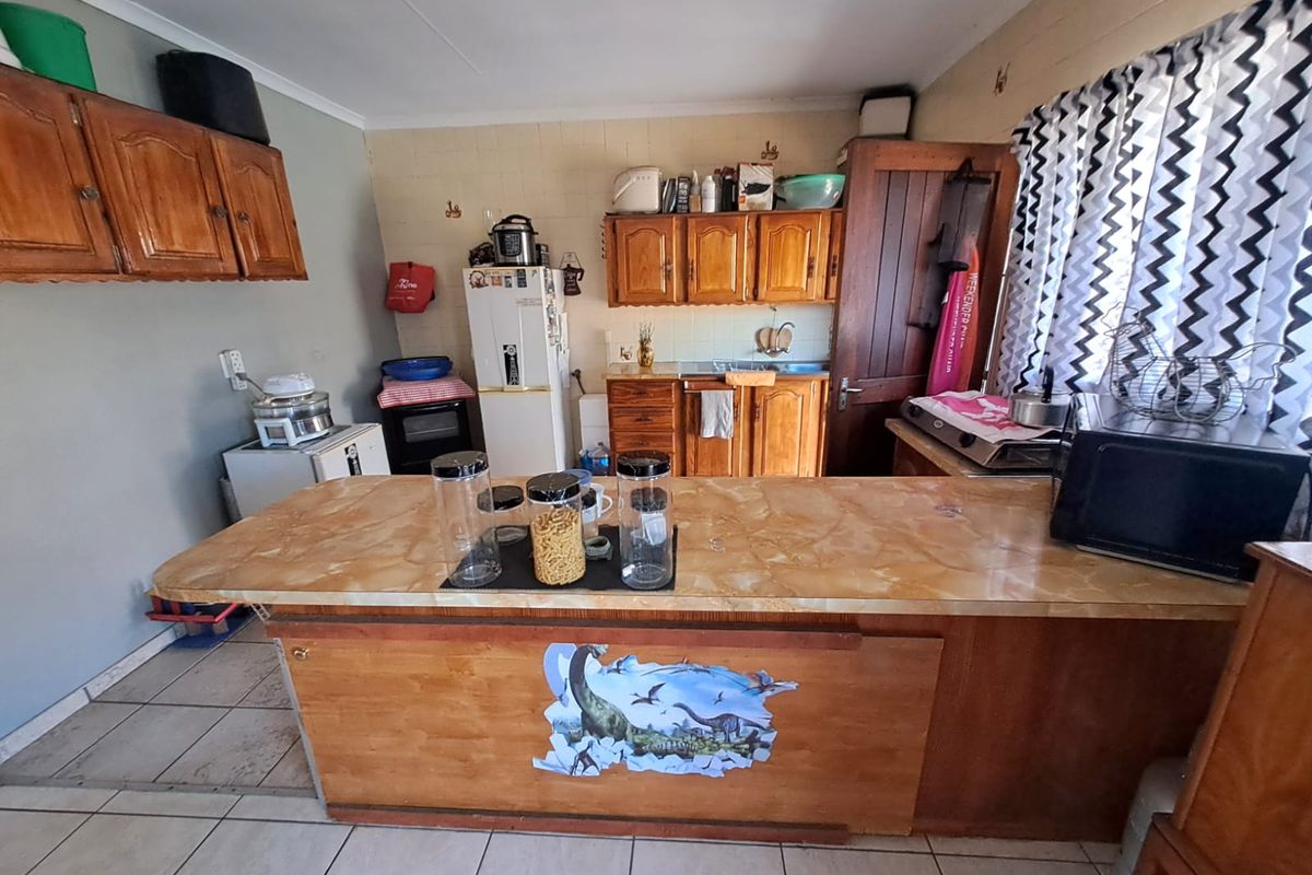 A dated kitchen featuring wooden cabinetry, a central island with a laminate countertop, and tiled flooring, offering potential for a modern renovation.