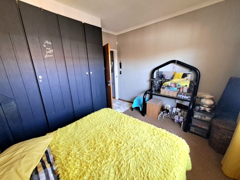 A bedroom featuring dark built-in cupboards, neutral wall finishes, and carpeted flooring.