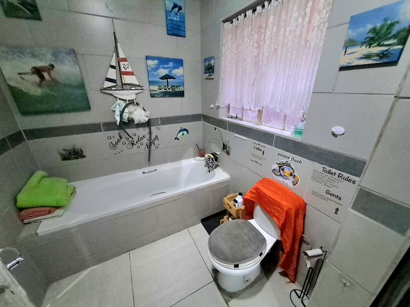 A functional bathroom featuring a built-in bathtub, toilet, and neutral ceramic tiling throughout.