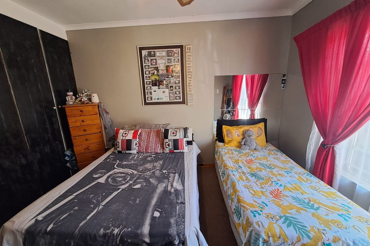 A functional bedroom featuring built-in cupboards and a ceiling fan, providing a practical space with standard finishes.