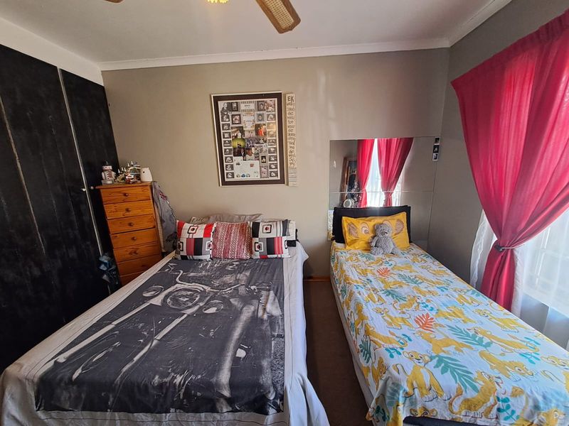 A functional bedroom featuring built-in cupboards and a ceiling fan, providing a practical space with standard finishes.