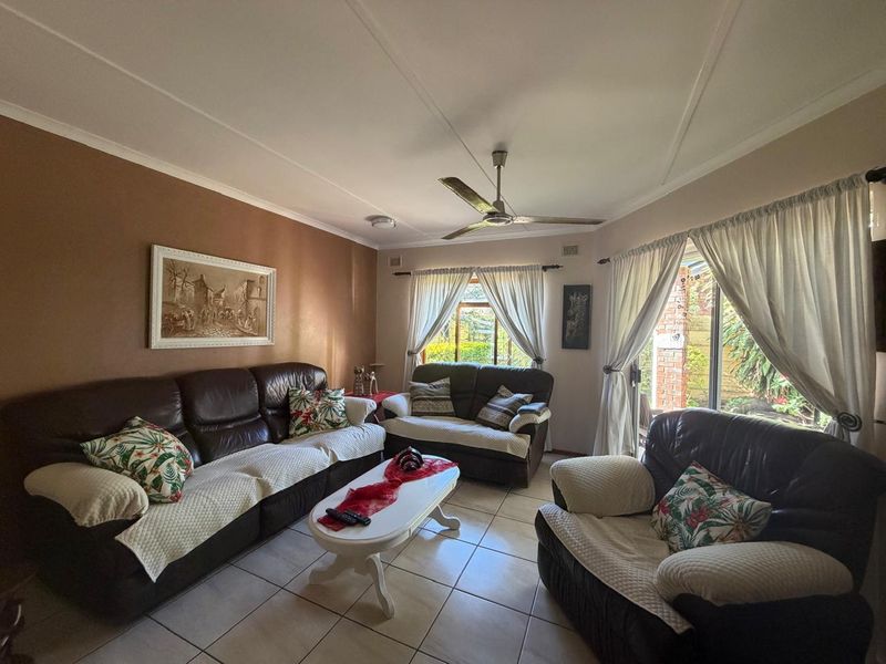 A comfortable living room featuring tiled flooring, a ceiling fan, and sliding glass doors that provide access to the outdoor area.