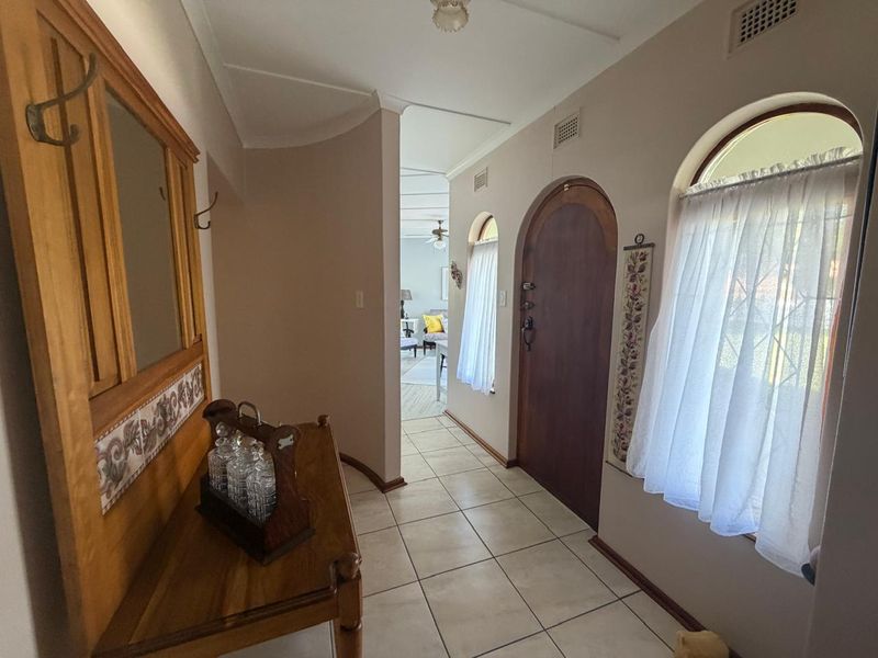Welcoming entrance hall featuring arched timber door, arched windows, and neutral ceramic floor tiles leading into the main living area.