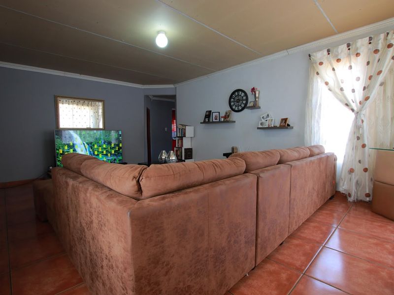 A living room featuring tiled flooring and panelled ceiling, providing a functional space for relaxation and entertainment.
