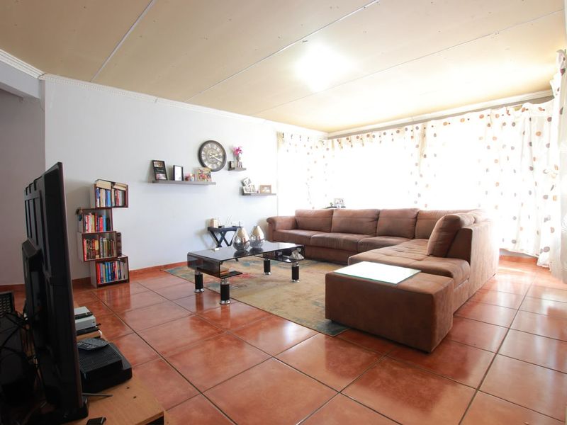 Spacious living room featuring terracotta-style floor tiles and panelled ceiling, offering a functional layout ready for modern updates.