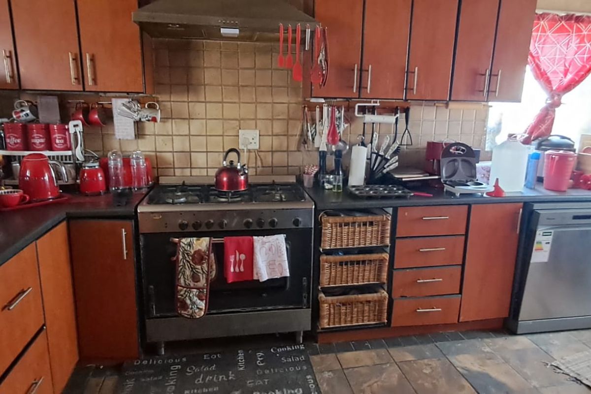 A functional kitchen featuring wooden cabinetry, a gas stove with extractor fan, tiled backsplash, and integrated dishwasher, offering a practical layout for daily cooking.