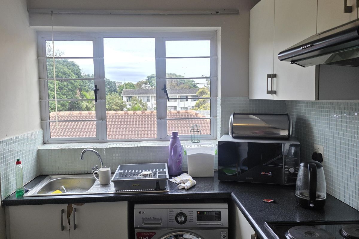 Compact kitchen featuring built-in cabinetry, laminate countertops, an electric hob with extractor fan, and a stainless steel sink with a window view.