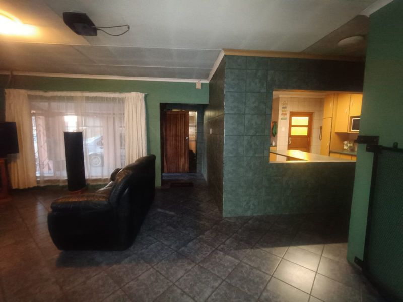 Open plan living area featuring tiled flooring and a tiled breakfast bar connecting to the kitchen, with direct access to an internal hallway.