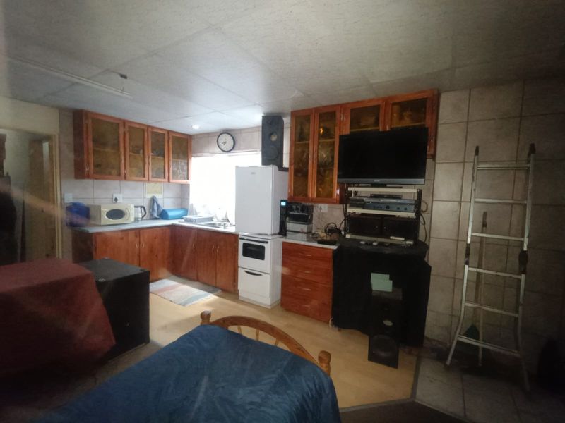A dated kitchen featuring wooden cabinetry, tiled walls, and built-in appliances, offering potential for a modern renovation.