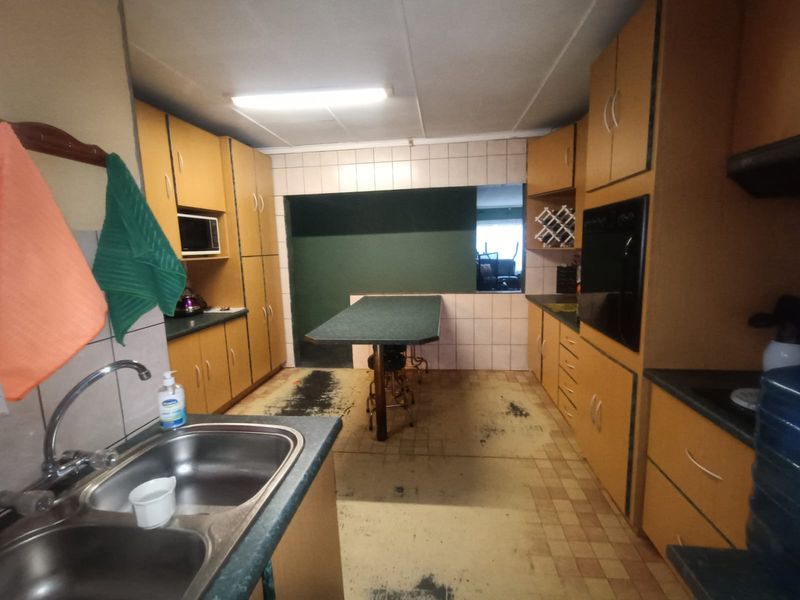 A dated kitchen featuring built-in cabinetry, a double bowl sink, integrated oven, and a breakfast bar, requiring cosmetic updates to modernize the space.