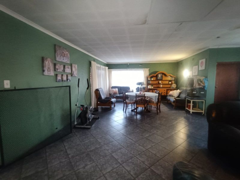 Spacious living area featuring dark tiled flooring and a large window, offering a versatile layout for comfortable family living.