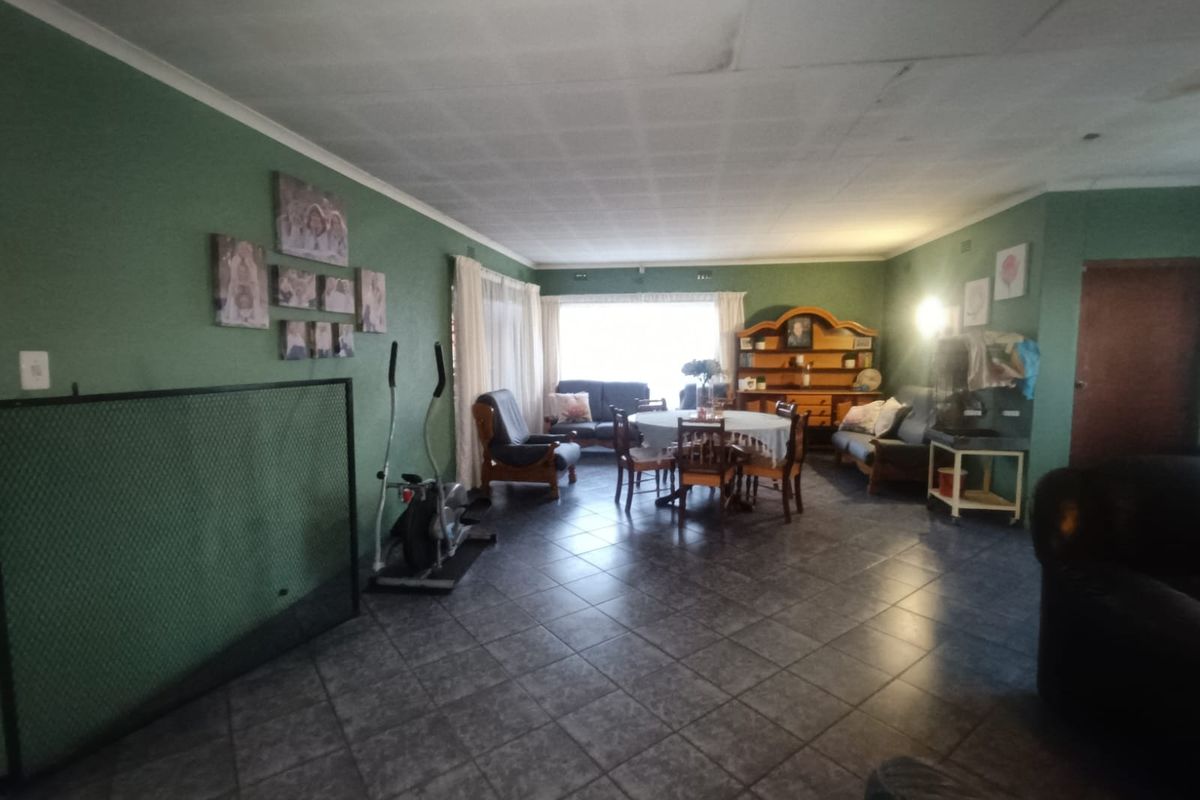 Spacious living area featuring dark tiled flooring and a large window, offering a versatile layout for comfortable family living.