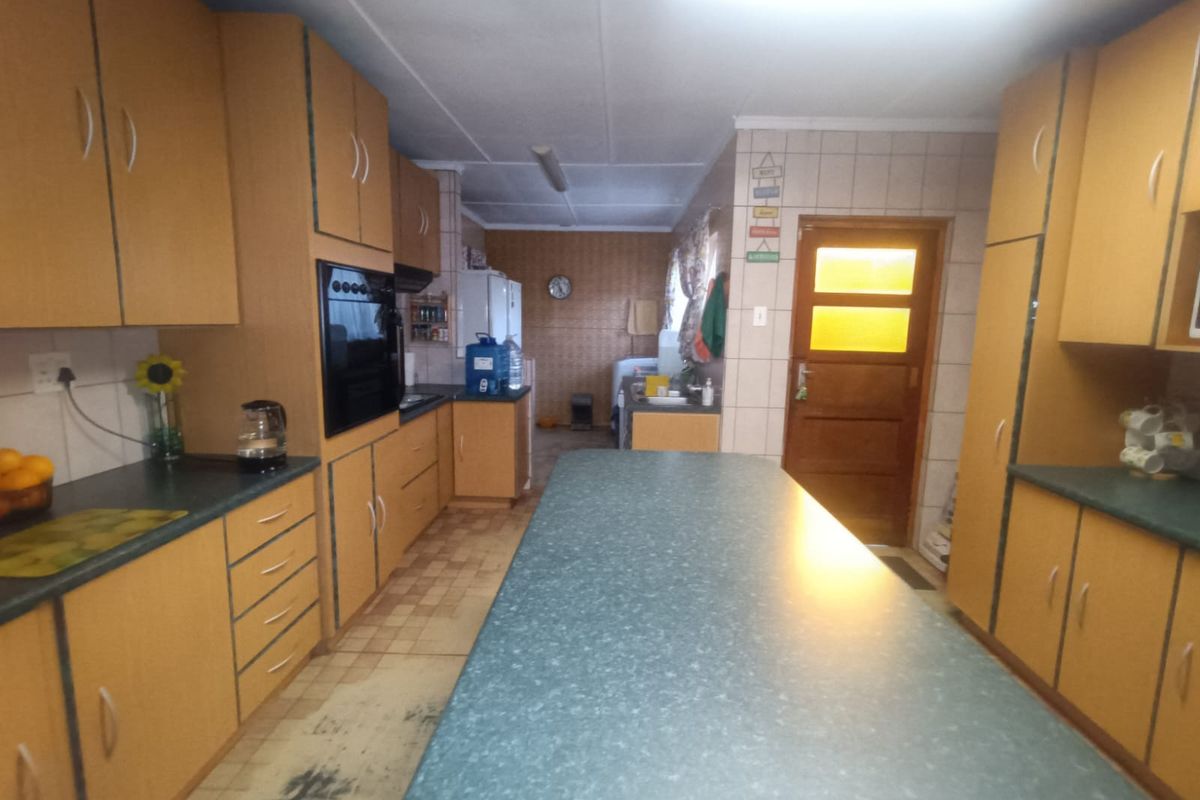 A spacious kitchen featuring extensive built-in cabinetry, laminate countertops, and a central island, offering a functional layout with potential for modern updates.