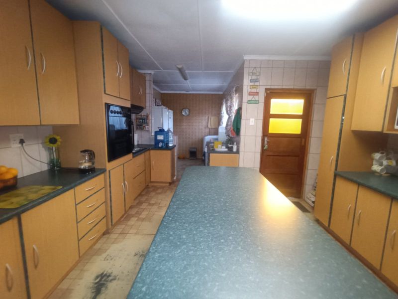 A spacious kitchen featuring extensive built-in cabinetry, laminate countertops, and a central island, offering a functional layout with potential for modern updates.