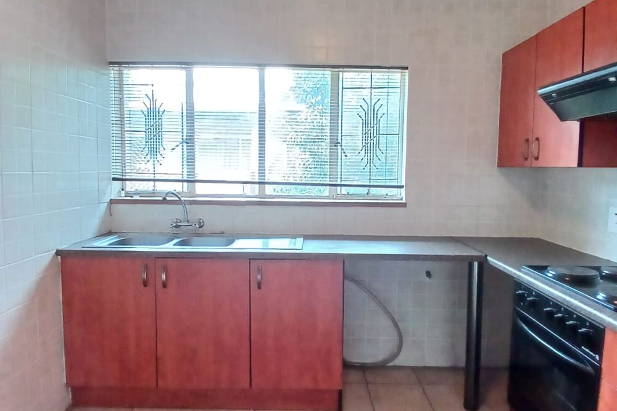 A functional kitchen featuring built-in cabinetry, a double sink, integrated oven and hob, and tiled finishes throughout.