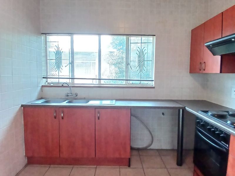 A functional kitchen featuring built-in cabinetry, a double sink, integrated oven and hob, and tiled finishes throughout.