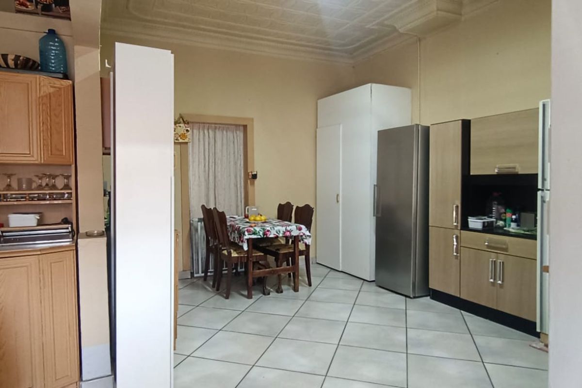 A functional kitchen area featuring tiled flooring, decorative ceiling details, and a mix of traditional and modern built-in cabinetry.