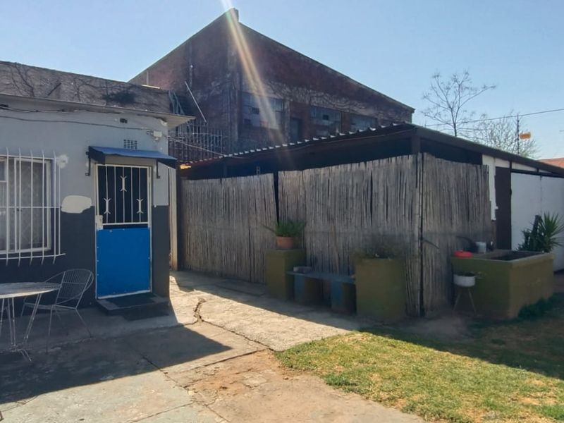 Rear exterior view of the property featuring a paved patio area, security bars on windows, and a precast concrete boundary wall.