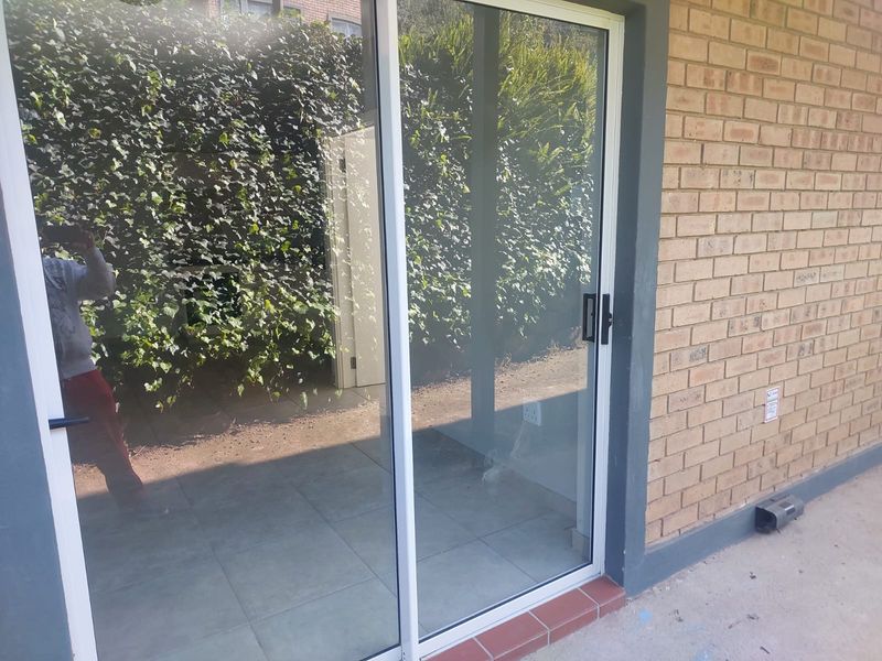 A view of a patio area featuring a sliding glass door and brick exterior wall, providing access to the outdoor space.