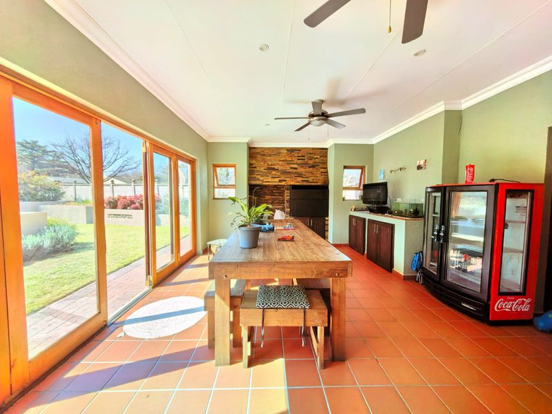 Spacious enclosed patio featuring terracotta tiling, built-in braai with stone cladding, and large stacking doors providing seamless access to the garden.