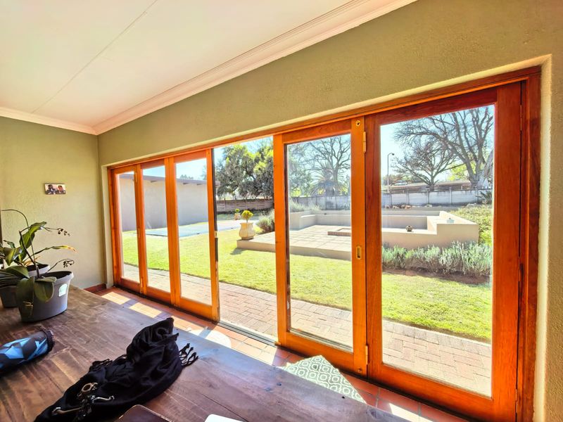 A bright indoor patio area featuring large wooden sliding doors that provide seamless access to the garden and pool area.