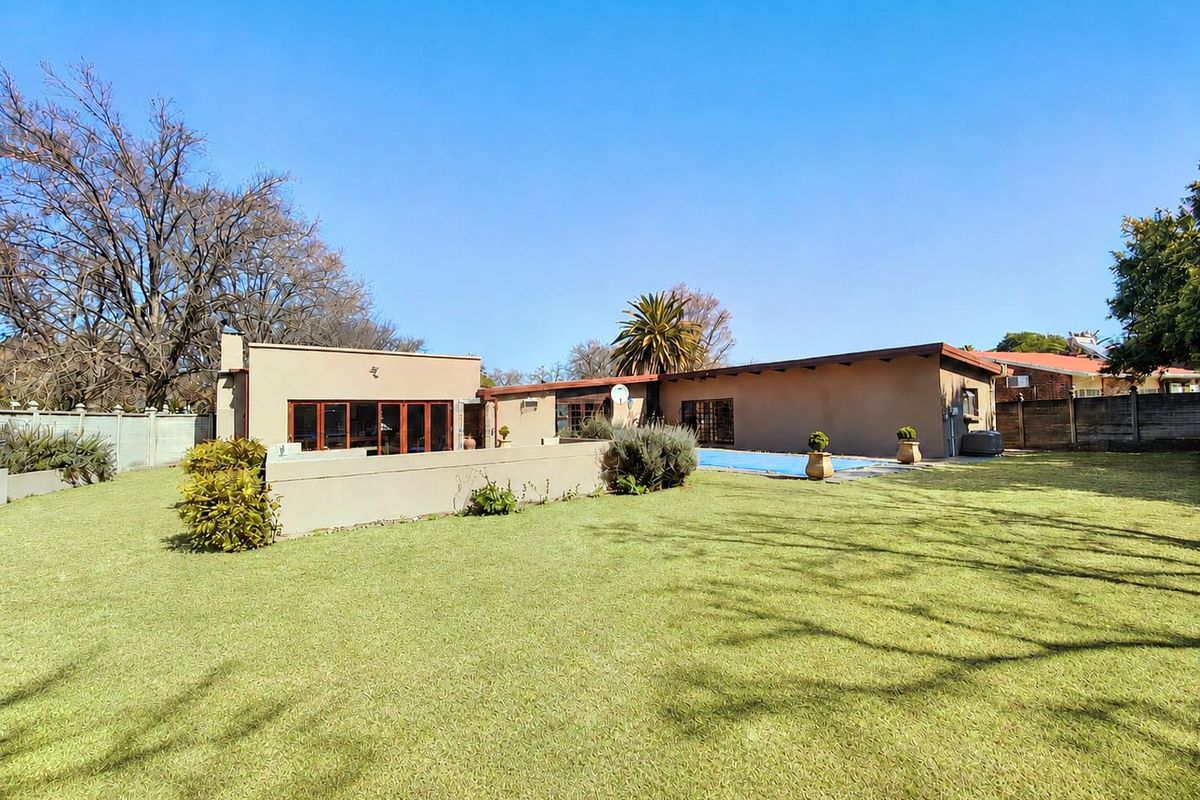 Spacious rear garden featuring a swimming pool, paved patio area, and direct access to the home through sliding doors.