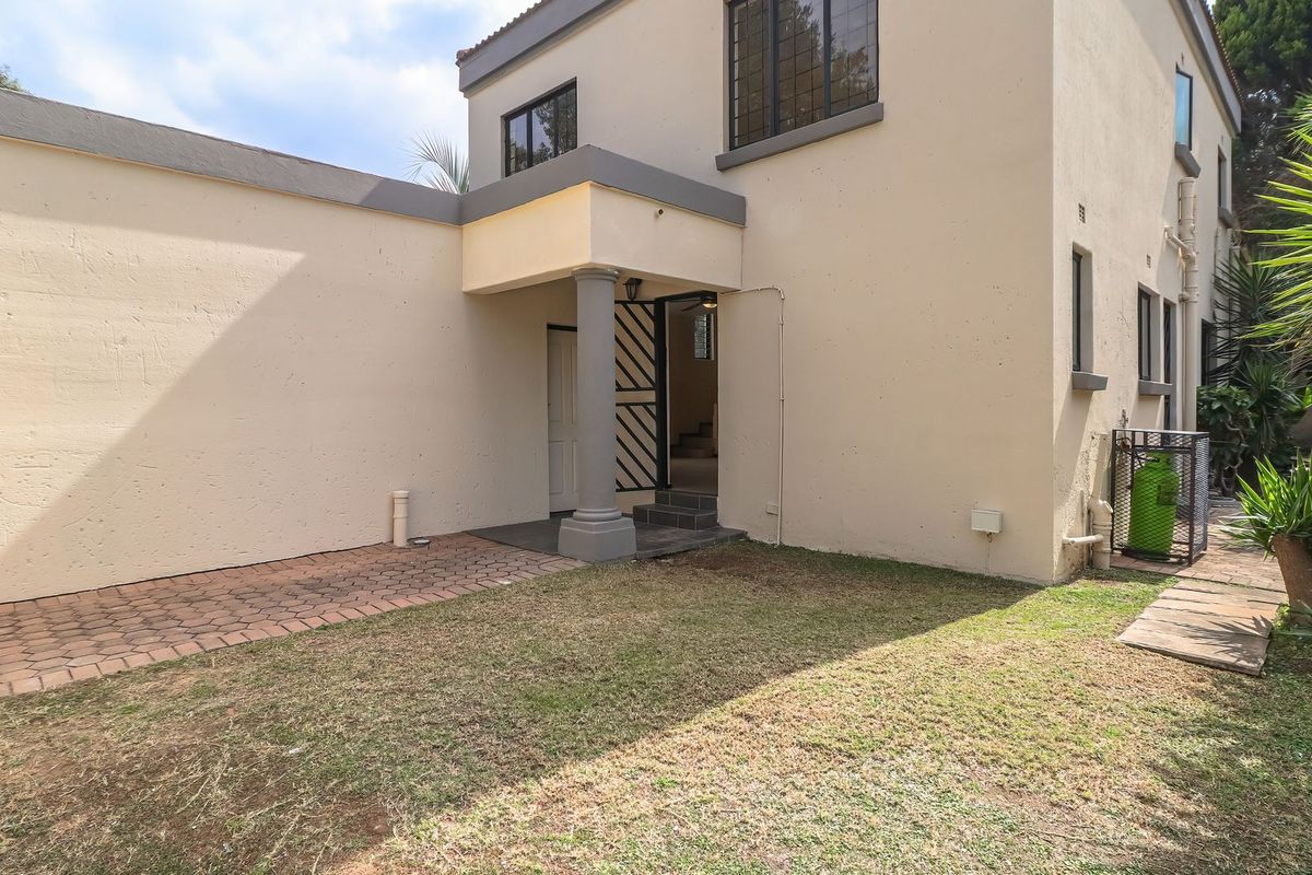 Rear exterior view of the house featuring a paved patio area, covered entrance with a structural column, and access to the garden.