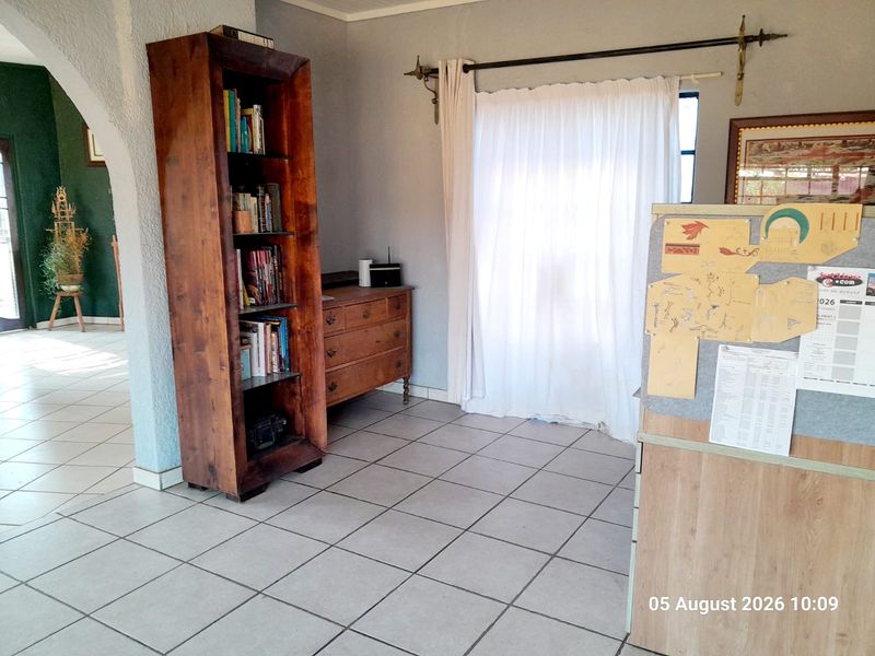 A living area featuring neutral tiled flooring and an arched architectural opening leading to an adjacent space.
