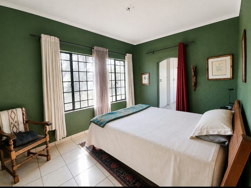 A bedroom featuring tiled flooring, steel-framed windows, and an arched doorway leading to a built-in cupboard area.