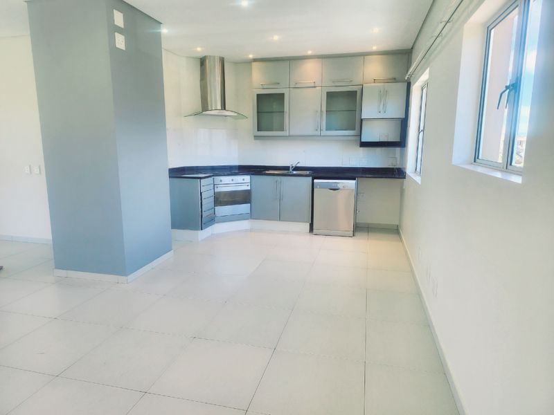 A clean, modern kitchen featuring built-in cabinetry, stainless steel appliances, and tiled flooring in an open-plan layout.