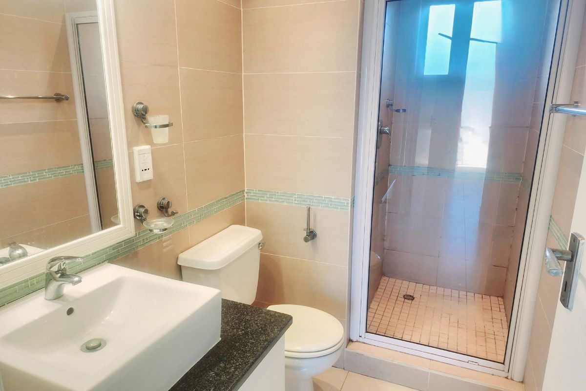 A clean, well-maintained bathroom featuring a vanity with granite countertop, ceramic basin, and a separate glass-enclosed shower with neutral wall tiling.