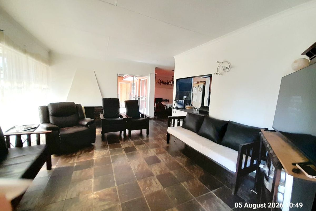 A living room featuring dark tiled flooring, a built-in fireplace, and a serving hatch connecting to the kitchen area.
