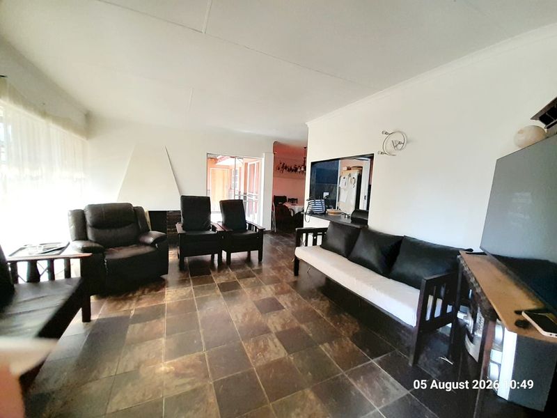 A living room featuring dark tiled flooring, a built-in fireplace, and a serving hatch connecting to the kitchen area.