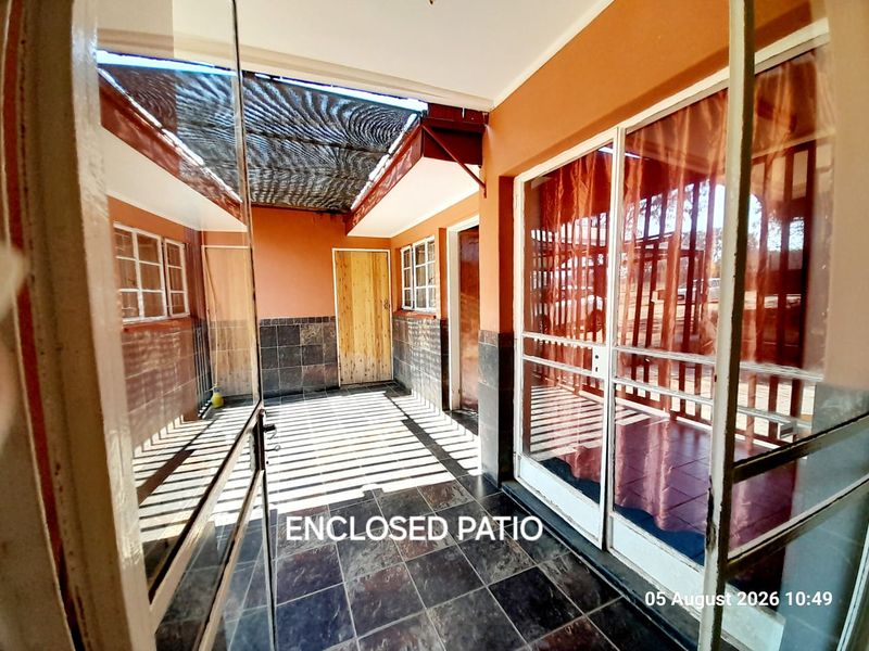 An enclosed patio area featuring tiled flooring, wall cladding, and sliding glass doors, providing a versatile transition space between the interior and exterior.