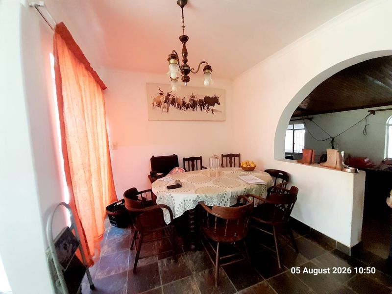 A dining room featuring tiled flooring and an arched opening leading to an adjacent space, illuminated by a central ceiling light fixture.