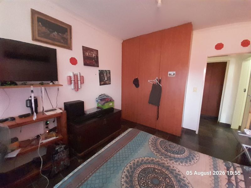 A bedroom featuring built-in wooden wardrobes and tiled flooring, offering a functional space with potential for modern updates.