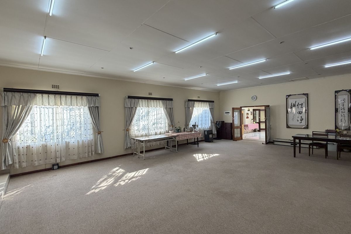 Spacious living area featuring neutral walls, large windows with natural light, and a combination of carpeted and tiled flooring.