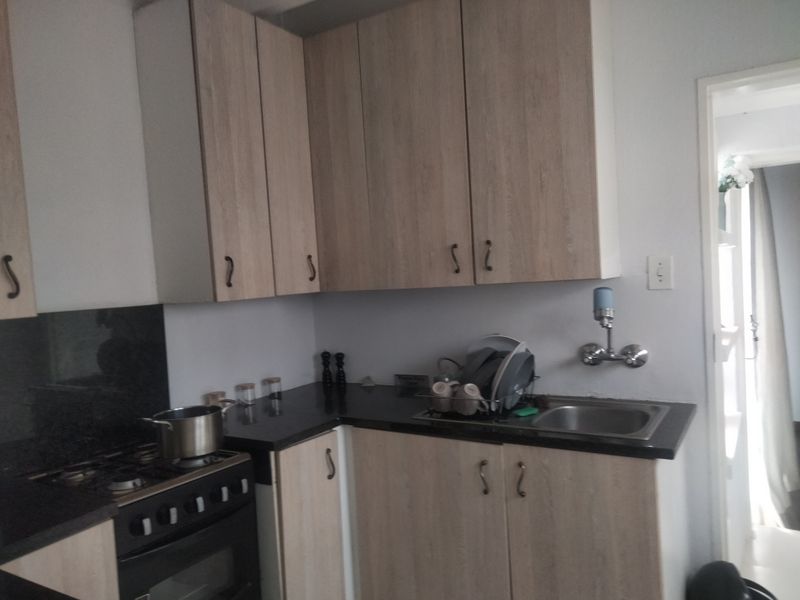 A functional kitchen featuring light wood-look cabinetry, dark countertops, a stainless steel sink, and a built-in gas stove with oven.