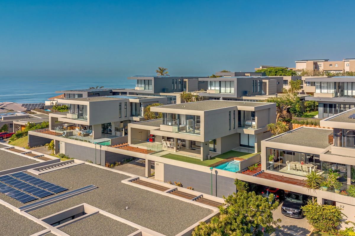 Aerial view of a modern townhouse complex featuring contemporary architecture, private swimming pools, solar panels, and scenic coastal views.