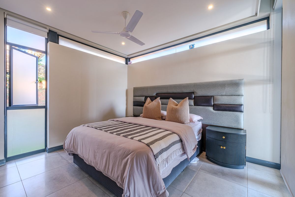 A modern bedroom featuring tiled flooring, a ceiling fan, and clerestory windows that provide natural light.