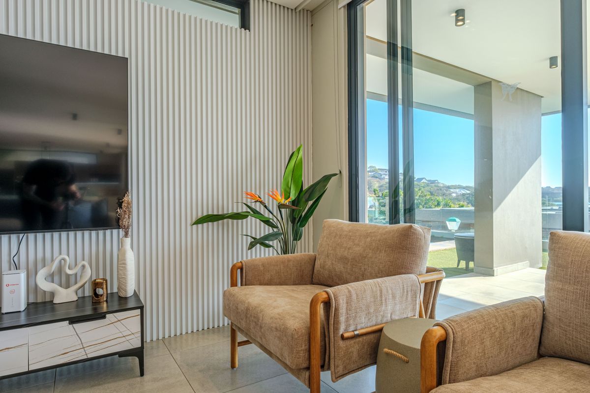 Modern living room featuring contemporary fluted wall paneling, large sliding glass doors providing natural light, and seamless access to an outdoor patio area.