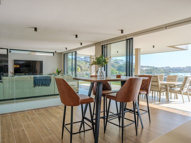 Modern open-plan living area featuring tiled floors, slatted wall detailing, and expansive sliding glass doors that open onto a spacious outdoor patio.