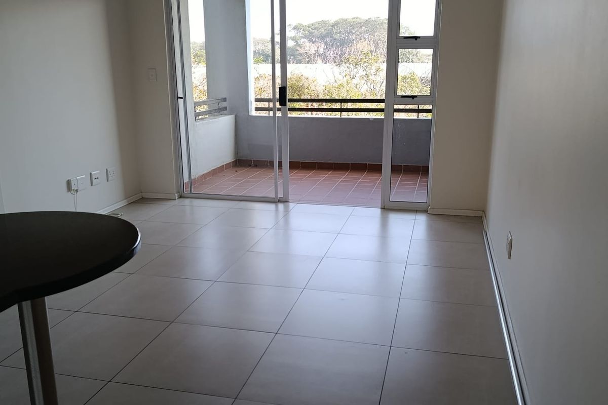 Bright and spacious living area featuring neutral tiled flooring and large sliding glass doors that open onto a private balcony.