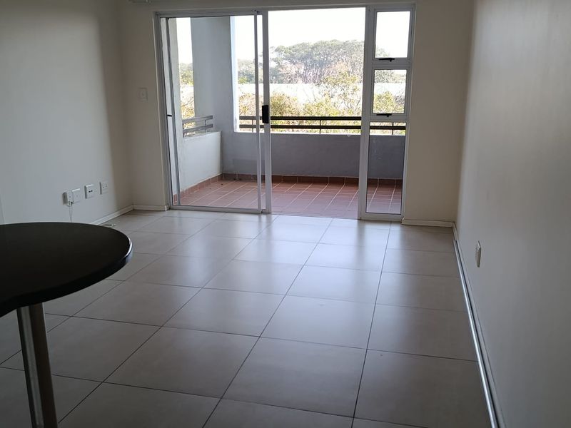 Bright and spacious living area featuring neutral tiled flooring and large sliding glass doors that open onto a private balcony.