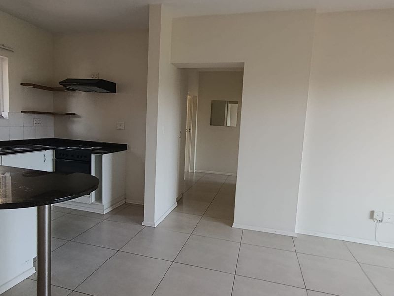 Open plan kitchen and living area featuring tiled flooring, granite countertops, built-in oven, extractor fan, and a breakfast bar.