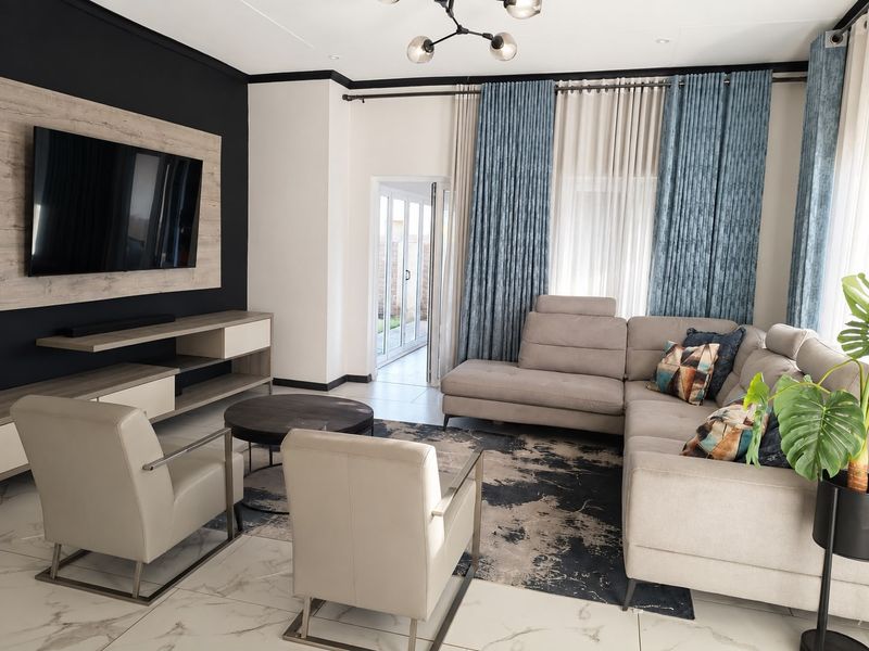 A modern, well-maintained living room featuring tiled floors, a built-in media unit, and direct access to an outdoor area through sliding glass doors.