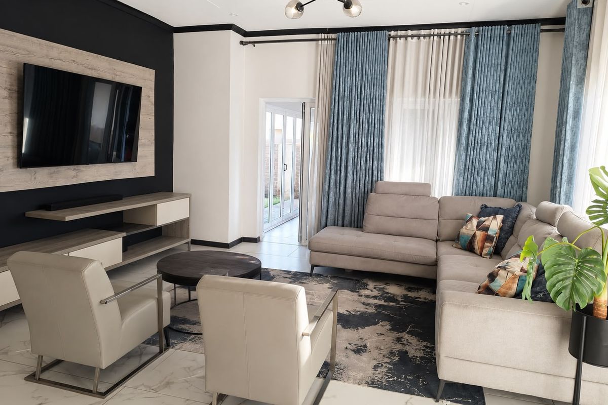A modern, well-maintained living room featuring tiled floors, a built-in media unit, and direct access to an outdoor area through sliding glass doors.