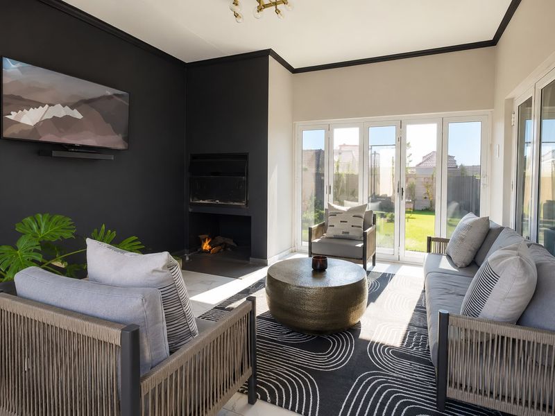 Modern living room featuring a built-in fireplace, dark accent wall, and large bi-fold doors providing seamless access to the rear garden.