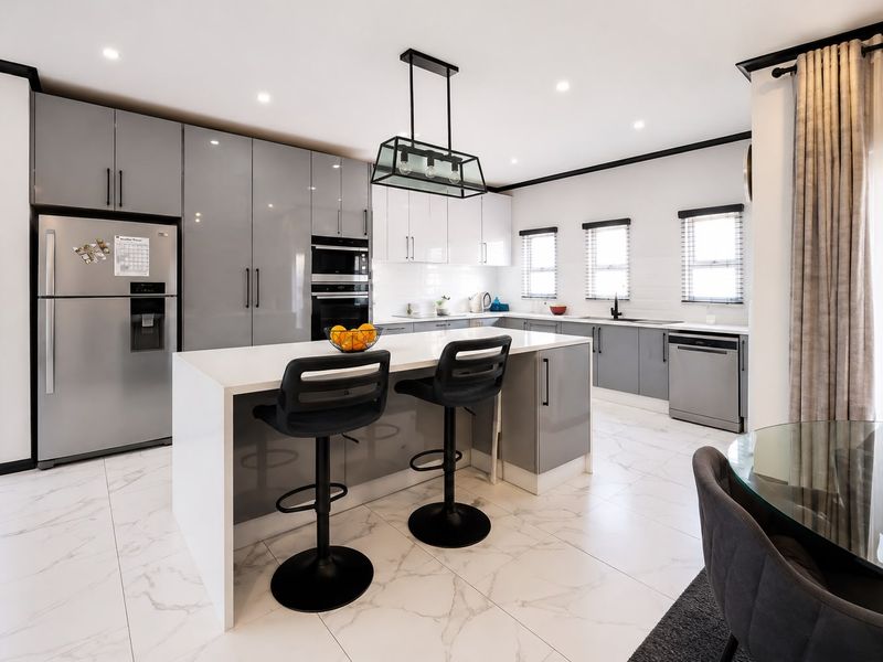 Modern kitchen featuring a central island, high-gloss cabinetry, integrated appliances, and elegant marble-look floor tiles in a bright, open-plan layout.