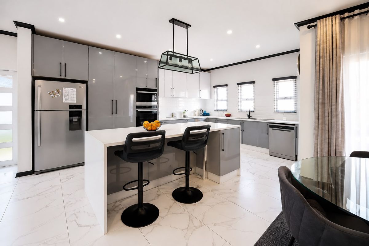 Modern kitchen featuring a central island, high-gloss cabinetry, integrated appliances, and elegant marble-look floor tiles in a bright, open-plan layout.